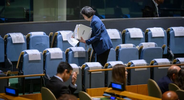 Сотрудница протокольной службы ООН обозначает зарезервированные места в зале Генеральной Ассамблеи.